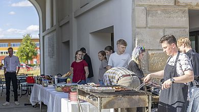 Menschen stehen am Grill