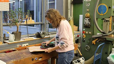 Eine Frau schleift ein Stück Holz