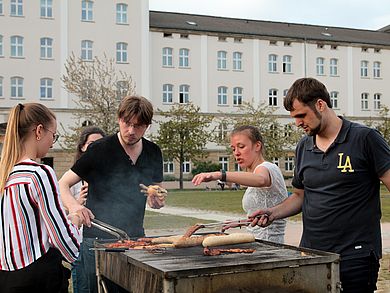 Vier Studierende stehen um den Grill