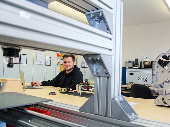 Studierender am Notebook und Adruino-Ameise