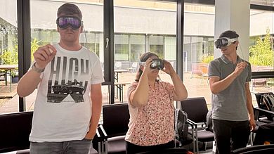 Hands-on in der Gruppe: Drei Teilnehmende erleben die Apple Vision Pro im Rahmen der Live-Demonstration und erkunden die intuitive Steuerung per Handgeste und Augensteuerung