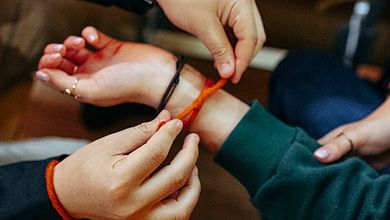 Ein schönes Symbol: Beim spirituellen Impuls banden sich alle Anwesenden als Zeichen des Zusammenhalts gegenseitig Bänder in der Farbe der Hochschule ums Handgelenk