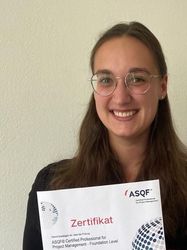 Die Studierende Sophie Armbruster mit ihrem ASQF-Zertifikat in der Hand