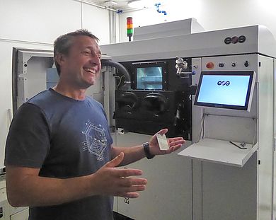 Mann steht vor 3D-Metalldrucker