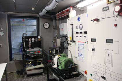 Das Bild zeigt die Prüfstandzelle 1 mit verschiedenen Motoren und Messgeräten.