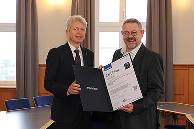Rudolf Miller (r.) vom TÜV Nord überreicht die Urkunde zur ISO-Zertifizierung an Hochschulpräsident Prof. Dr. Clemens Bulitta (l.)