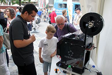 Zwei Besucher nehmen den 3D-Drucker in Augenschein.