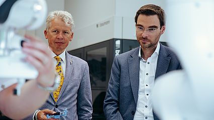 Im Montagebereich der SAPbased Smart Factory zeigen Wissenschaftler der OTH Amberg-Weiden Hochschulpräsident Prof. Dr. Clemens Bulitta (l.) und MdL Dr. Stephan Oetzinger (r.) wie unter anderem an Mensch-Maschinen-Interaktionen praxisnah geforscht wird