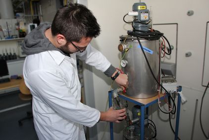 Ein Student untersucht verschiedene Substrate um daraus Biogas zu erzeugen.