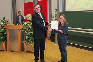 Prell übergibt Urkunde an Studentin