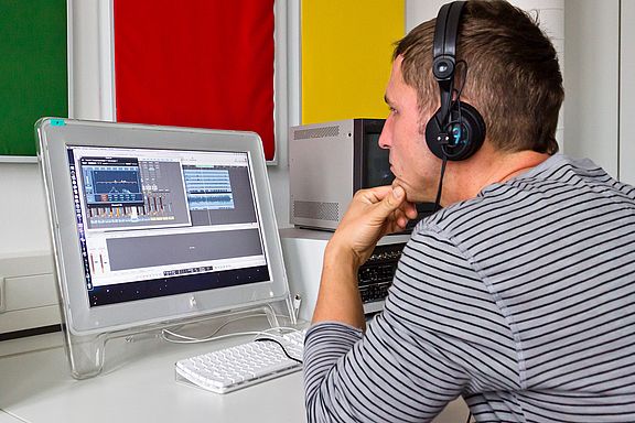 Student mit Kopfhörern am Computer des Labors für Audio- und Videotechnik