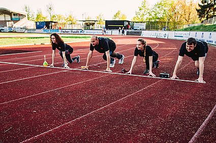Vier Studierende auf der Laufbahn in Startposition