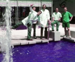 Männer stehen an einem Wasserbecken mit lila Boden